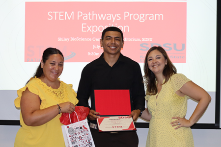 Two female program directors stand on either side of student participant in STEM Pathways Program